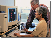 Senior woman working at a PC while senior man looks on